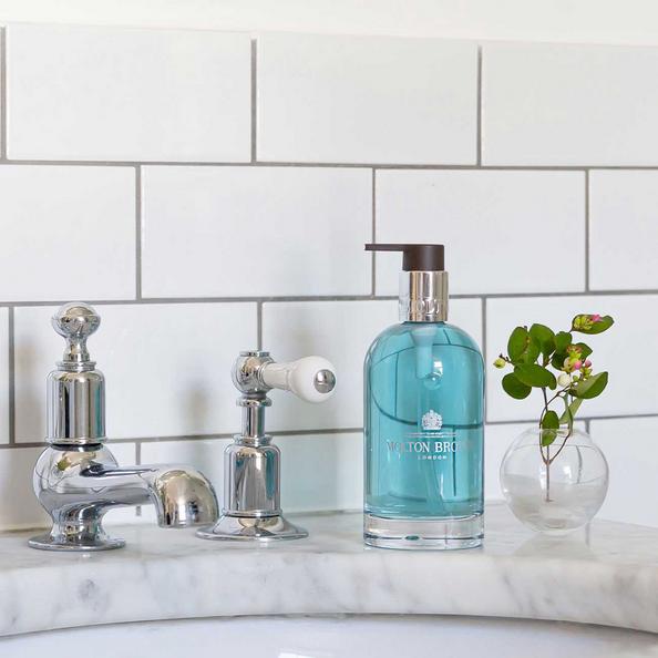 An image of a Bottle of Molton Brown Coastal Cypress & Sea Fennel Hand Wash on a sink